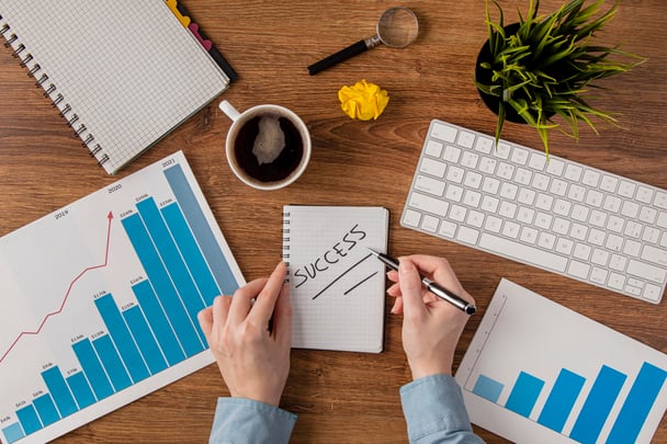 top-view-office-desk-with-growth-chart-hands-writing-success